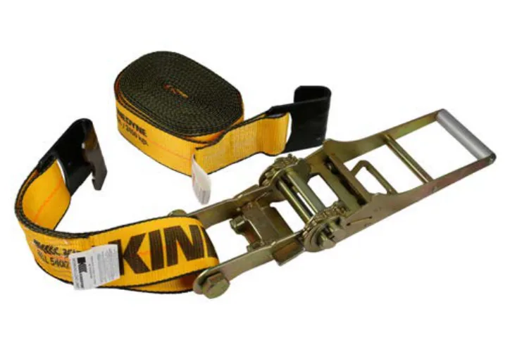 A Kinedyne ratchet strap coiled beside its ratchet, with flat hooks on both ends and the working load limit stenciled along the yellow webbing