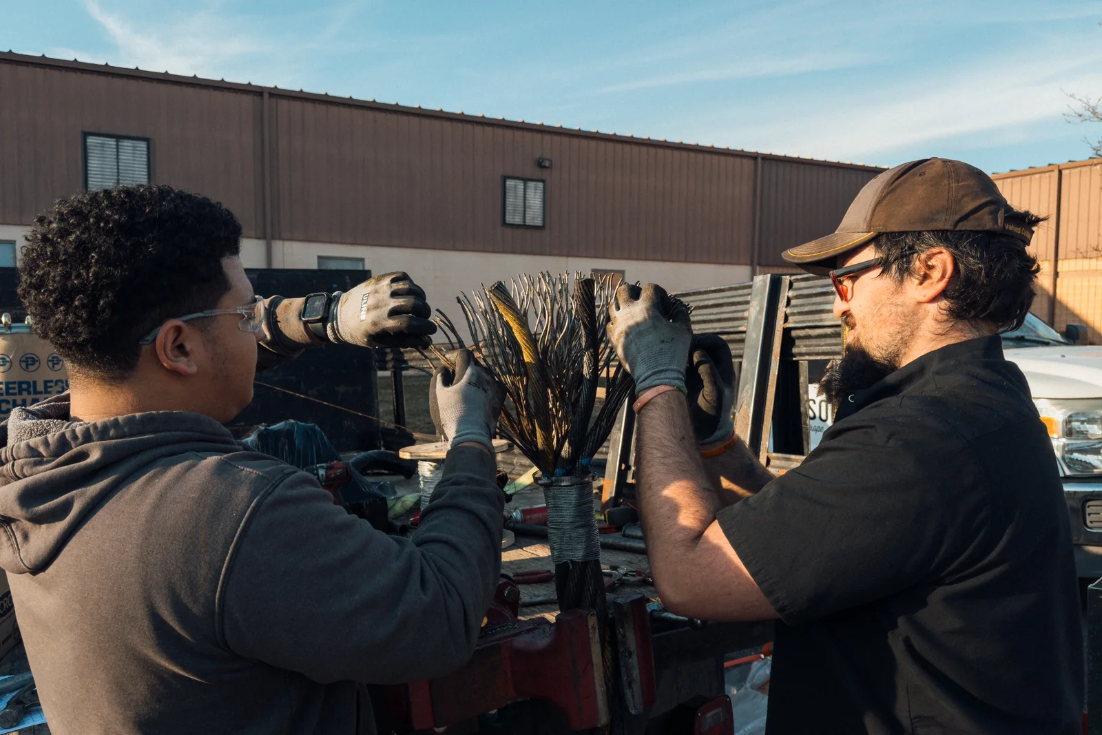 Two Nelson technicians preparing broomed rope ends side by side on the bench outside the Hatfield shop