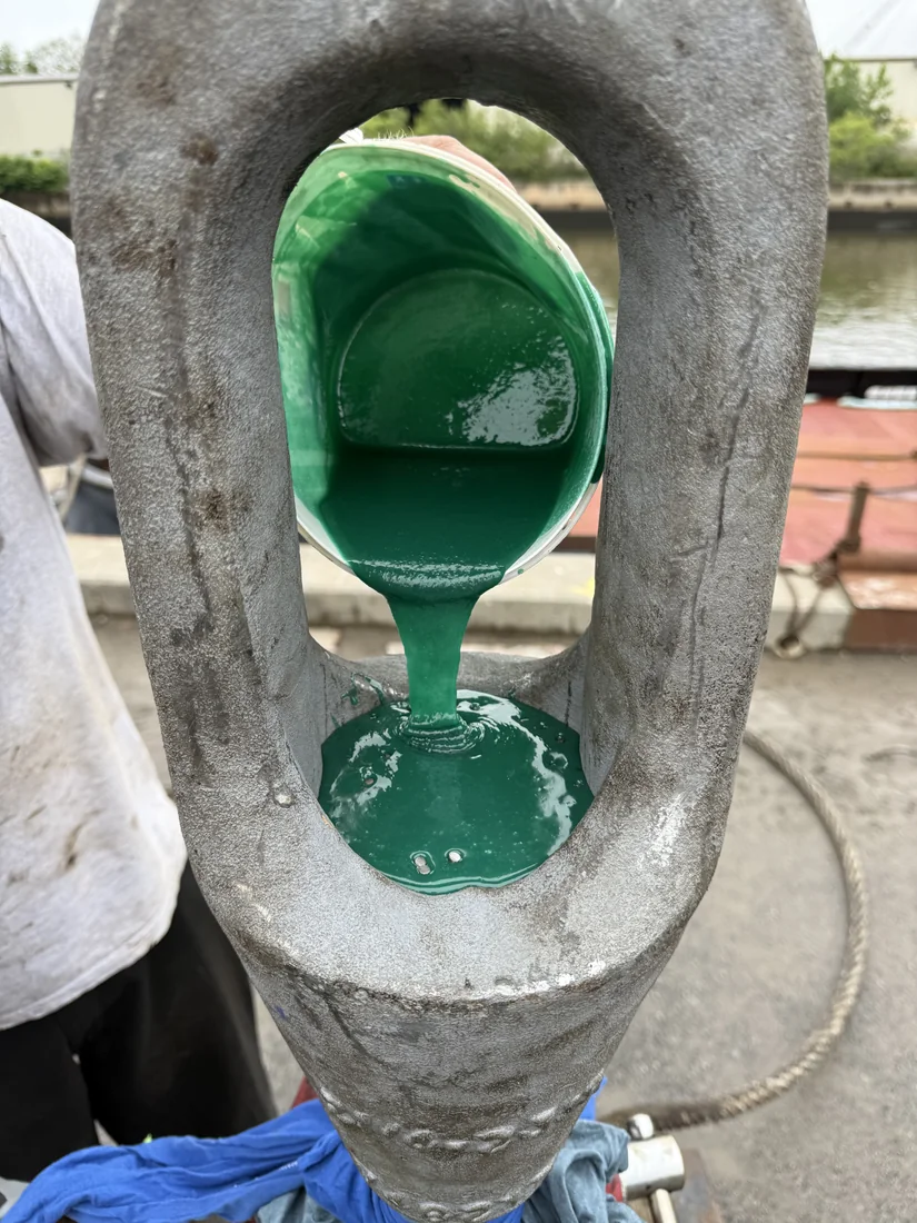 Resin being poured from a mixing pail into the basket of an open spelter socket at the dock