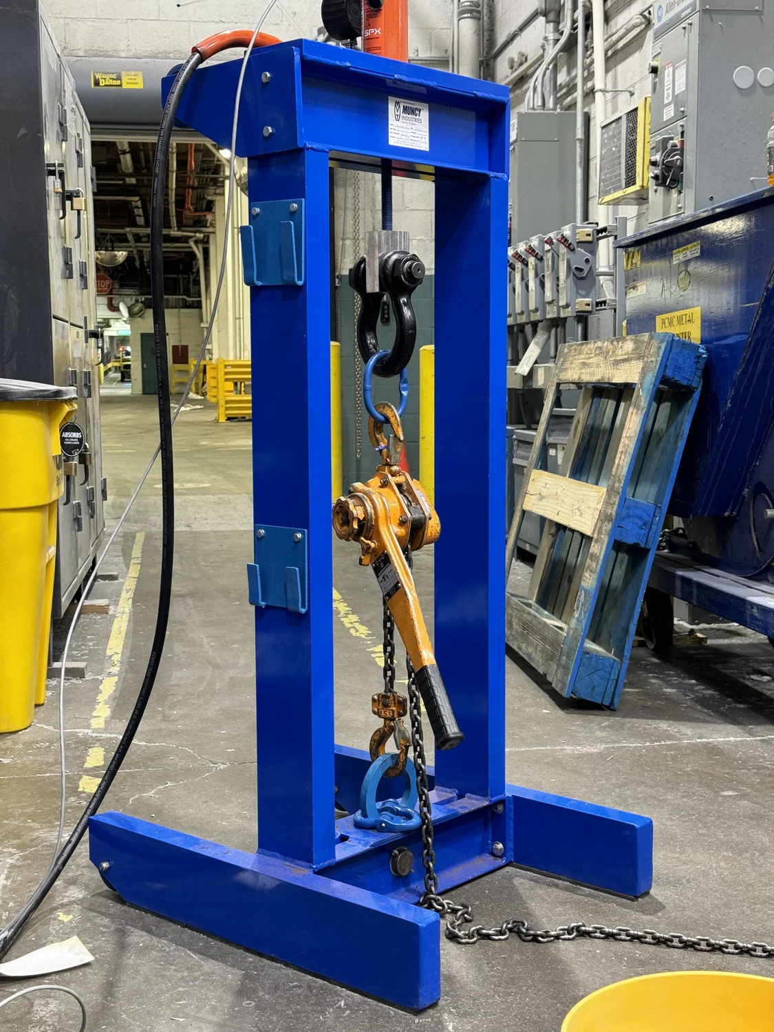 The Nelson mobile proof test frame: a welded blue steel frame on a wide base, with a shackle, master link and lever hoist rigged inside it and a chain running out to the load
